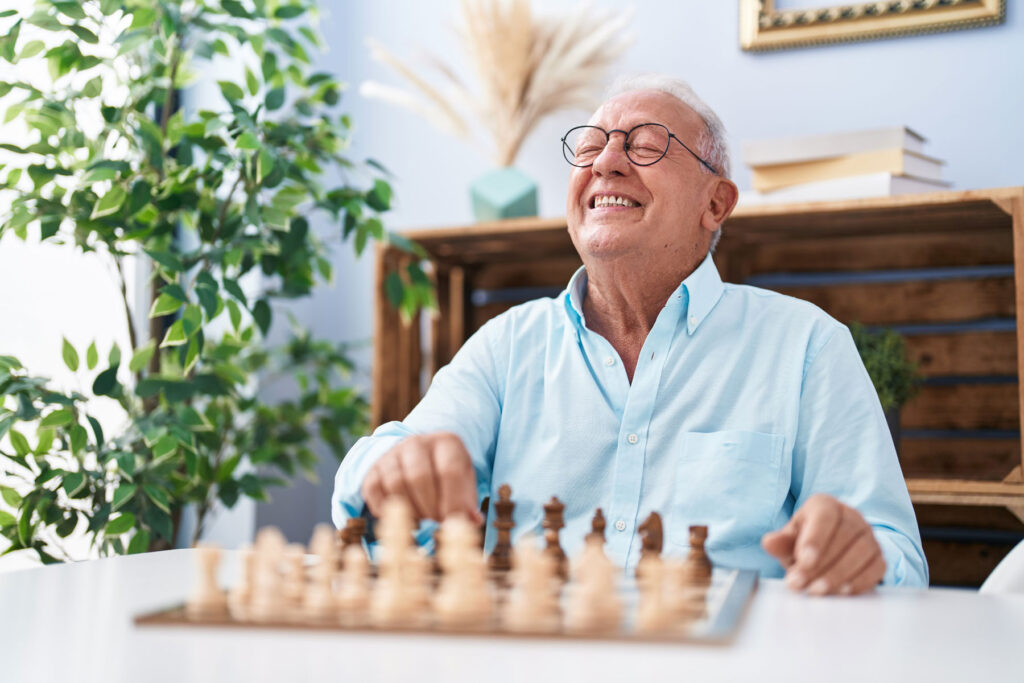 person smiling while playing chess as one of many brain exercises for seniors