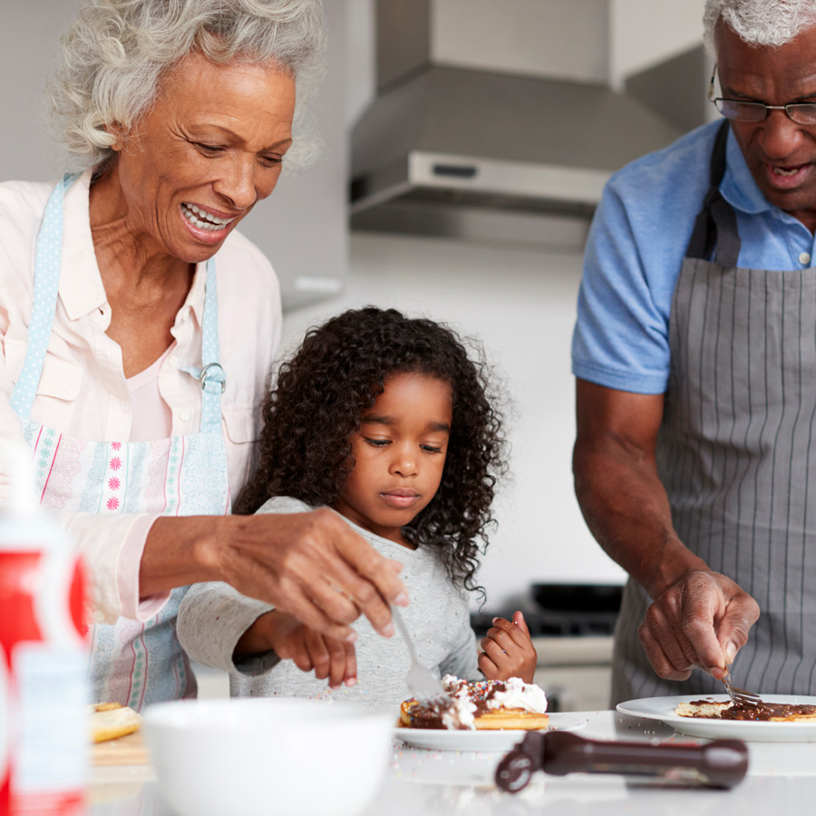 grandparents make dessert with their granddaughter who is visiting them in senior living