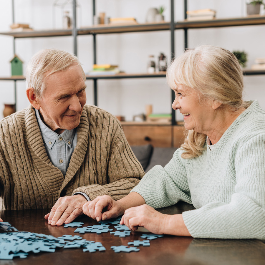 an elderly couple works on a puzzle together