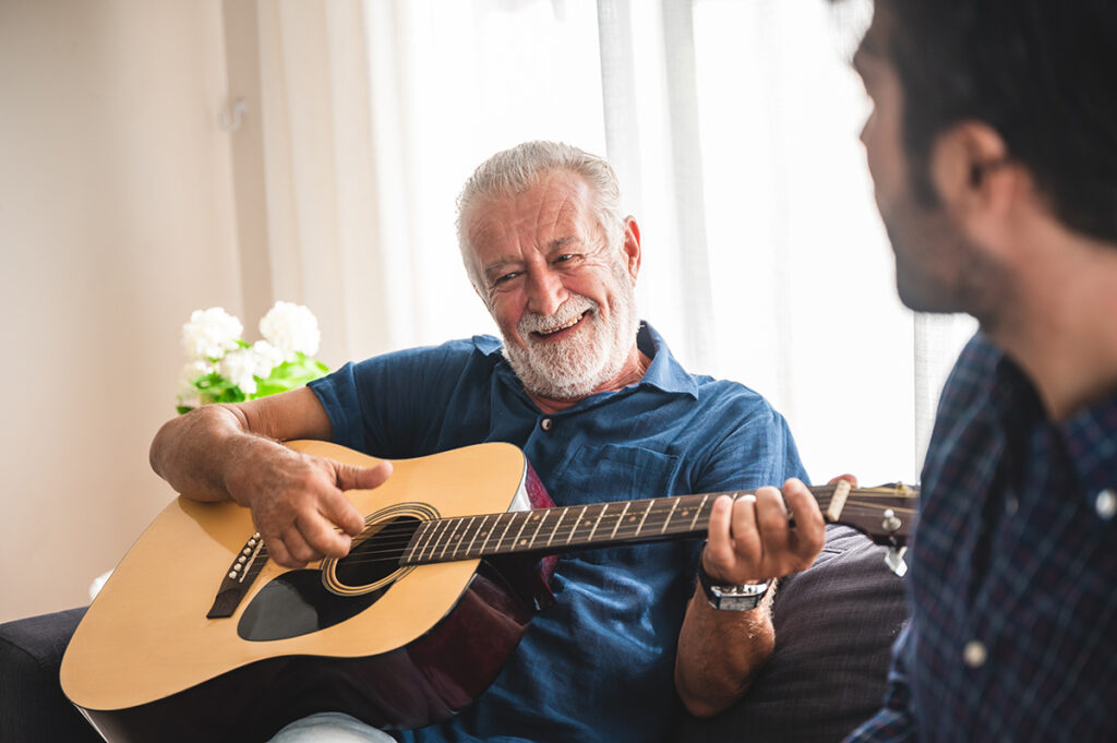 a senior man plays guitar for guests