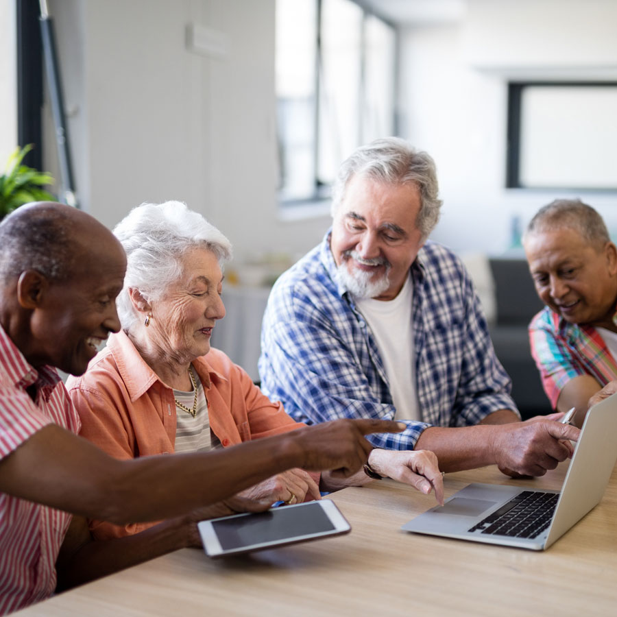 a senior friend group meets up with their laptops and tablets