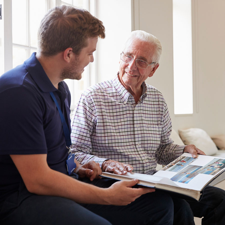 a senior man shows an activity aide a photo album full of memories