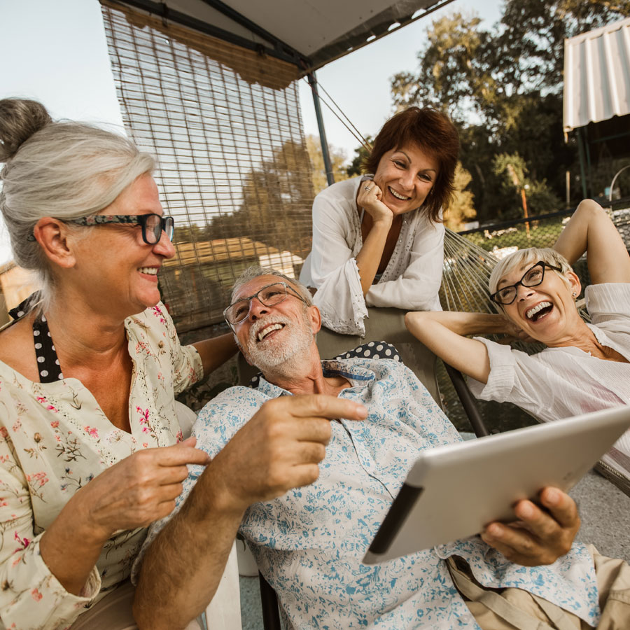 a senior friend group watches something funny on a tablet