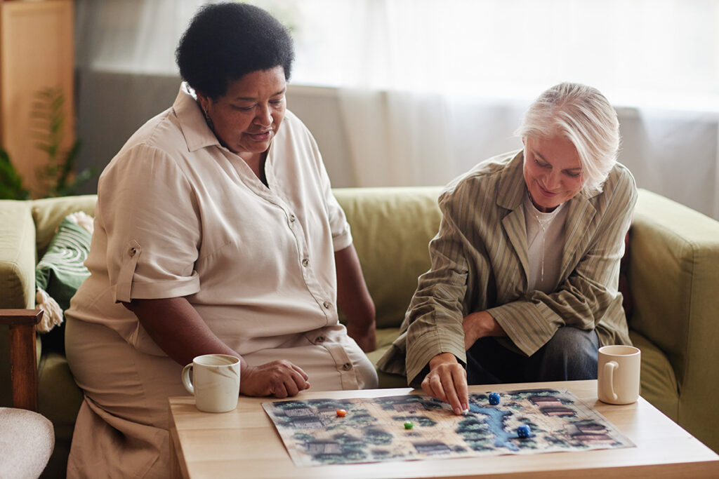 two senior women play a board game over coffee