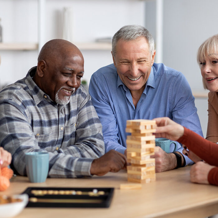 a group of seniors plays jenga together at game night in assisted living