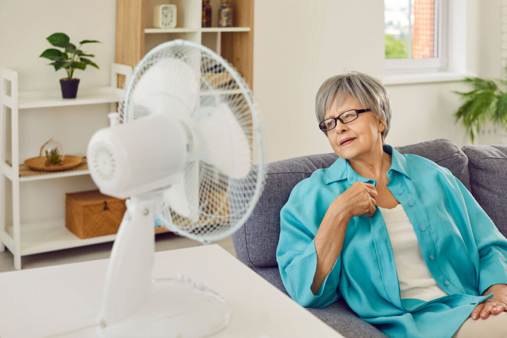 person near fan practicing hot weather safety