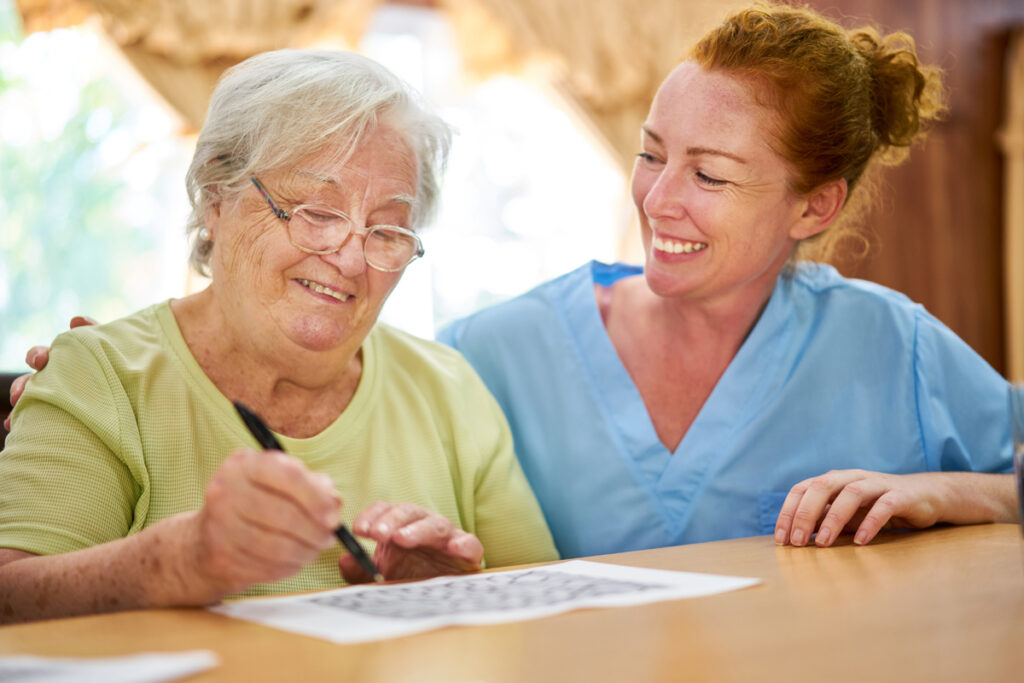 medical professional and older adult woman sit together smiling and talking about respite care vs assisted living