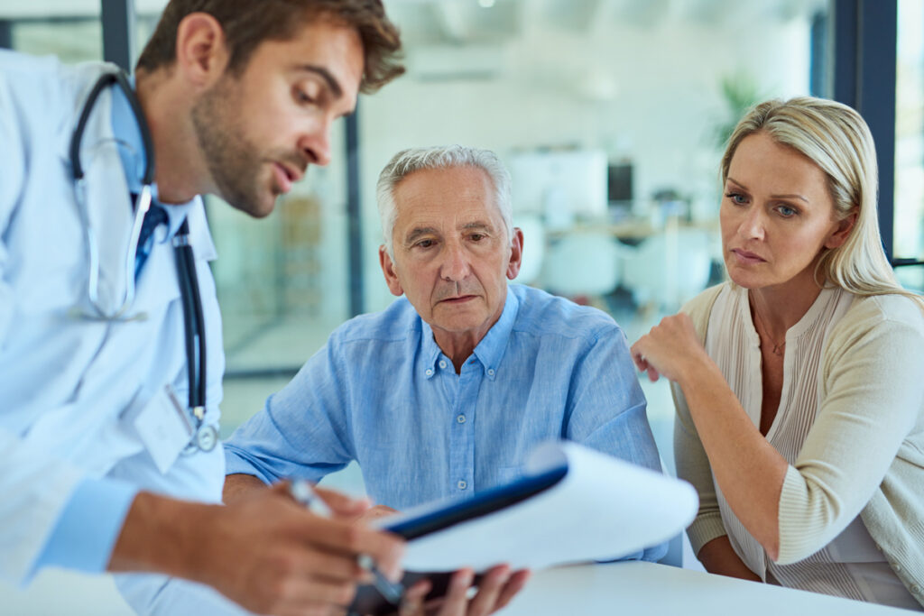 Woman with elderly father speaking to doctor
